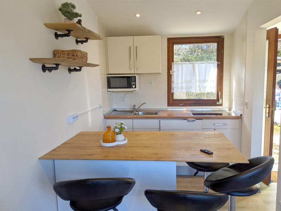 Moderne Küche im Ferienhaus Moderne Küche mit Holzarbeitsfläche, Mikrowelle und drei schwarzen Barstühlen.