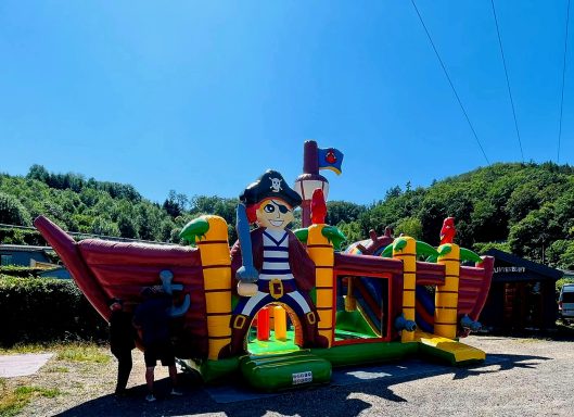 Piraten-Spielburg in bunten Farben mit Figuren und Rutsche im Freien.