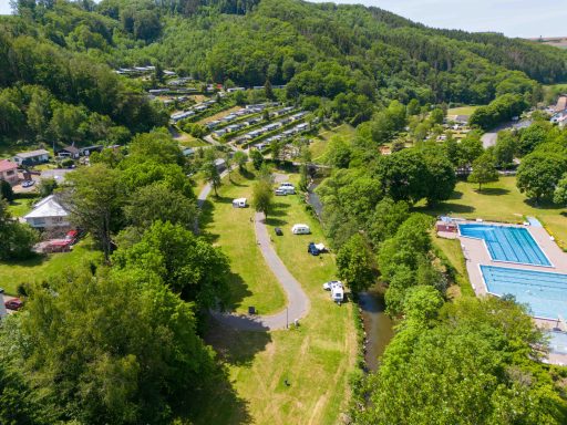 Grüne Landschaft mit Campingplätzen, Schwimmbad und Wanderwegen.