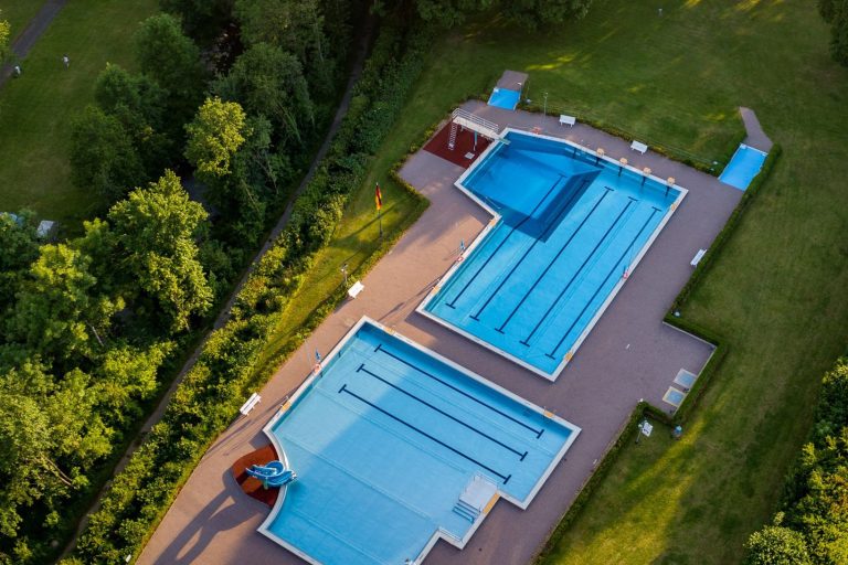 Blick auf das Freibad | Ferienpark Eifel Zwei Schwimmbecken umgeben von Grünanlagen, aus der Vogelperspektive.