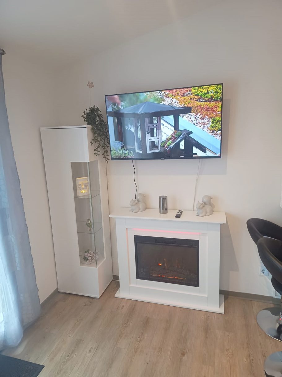 Kaminheizung und Smart-TV im Wohnzimmer Moderner Wohnraum mit Fernseher über einem Kamin und einer eleganten Dekoration.
