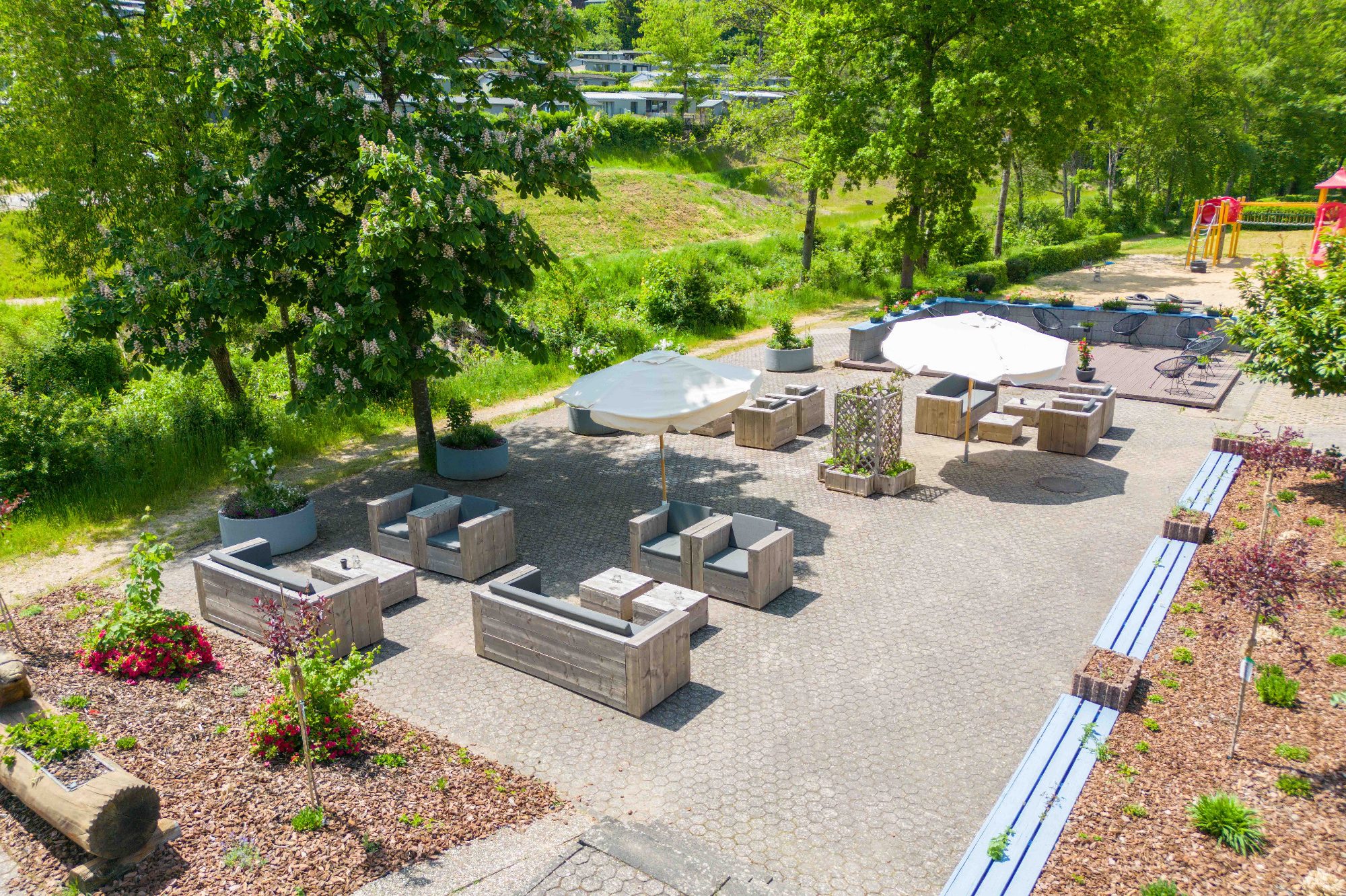 Gartenbereich mit Sitzgelegenheiten, Tischen und Spielplatz im Ferienpark