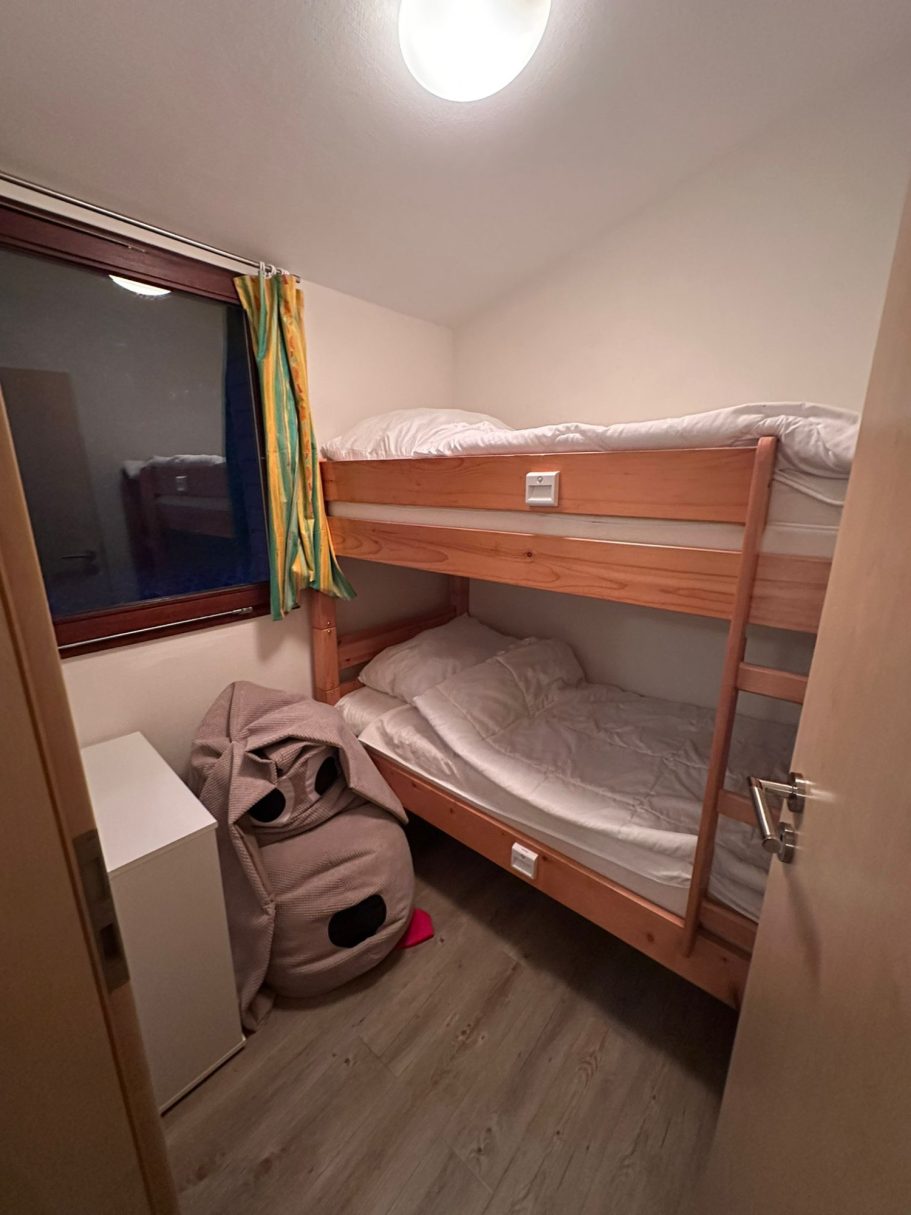 Das 2. Schlafzimmer im Ferienhaus Kleines Zimmer mit Etagenbett, Schrank und einem großen Kissen in der Ecke.