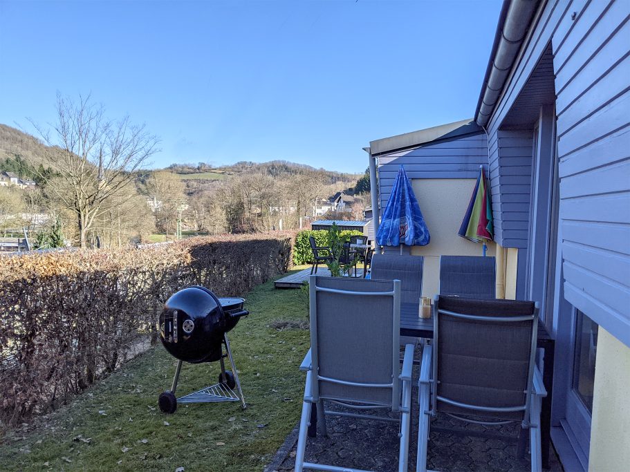 Die Terrasse mit Grill vom Ferienhaus Terrasse mit Liegestühlen, Grill und Blick auf den Garten und die Hügel im Hintergrund.