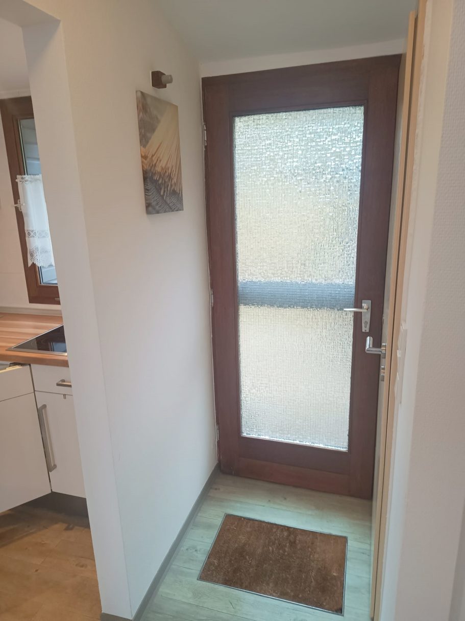 Der Flur und Eingang vom Ferienhaus Tür mit Milchglas und schicken Fußmatte in einem hellen Raum.