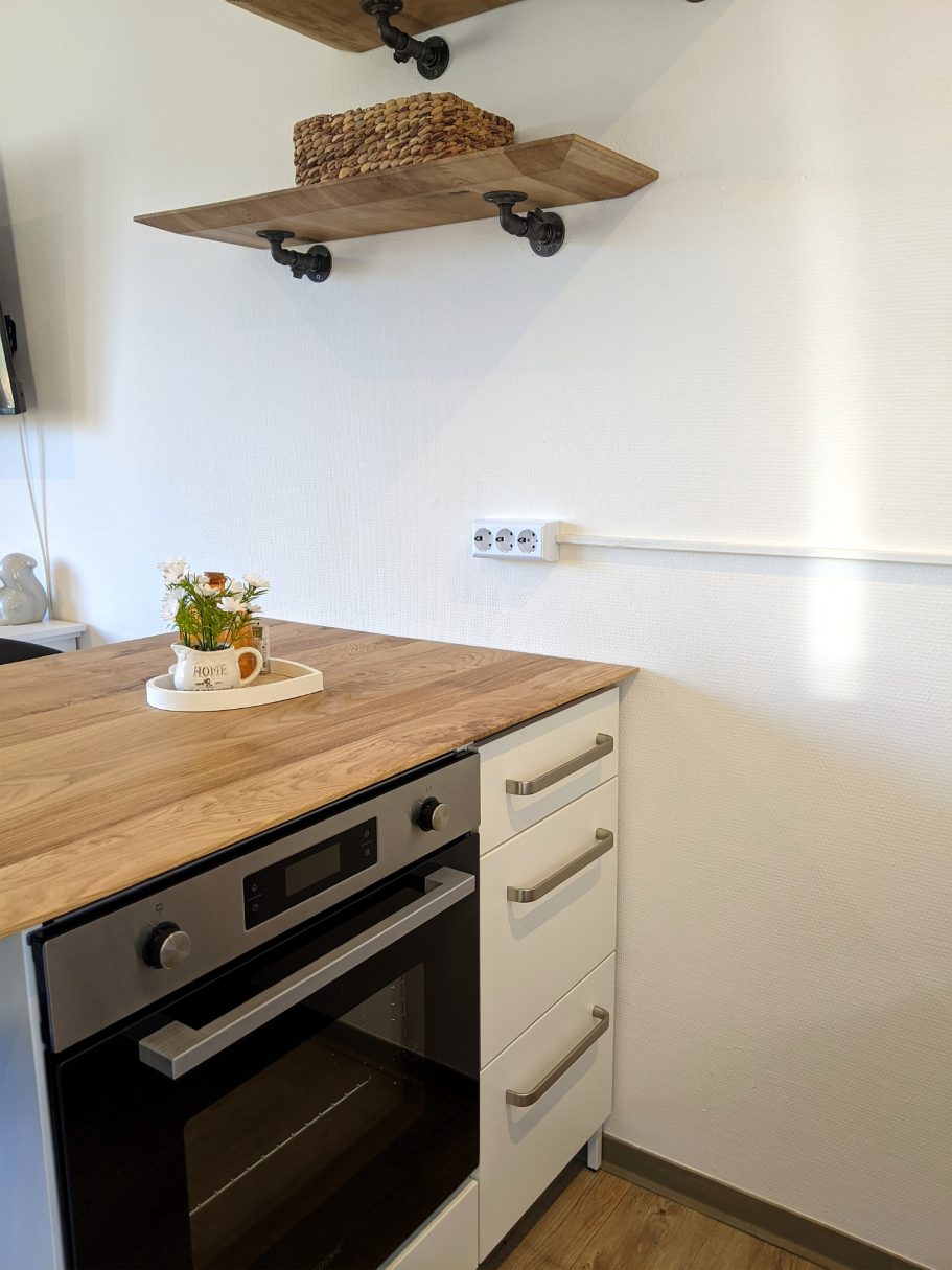 Die Küche im Ferienhaus Moderne Küche mit Holzarbeitsplatte, Backofen und dekorativem Obstarrangement.