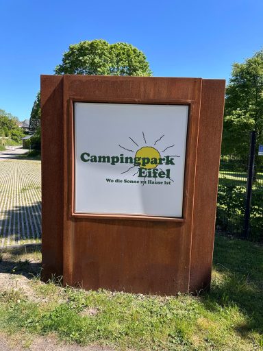 Schild des Campingpark Eifel mit Sonnensymbol und Kontaktinformationen.